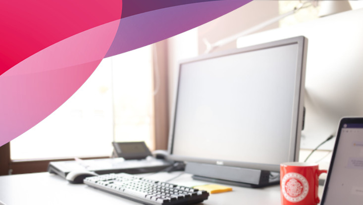 Ansicht eines Arbeitsplatzes mit PC und UHH Tasse