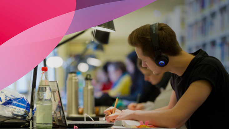 Student listening and writing in the library