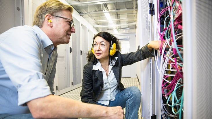 A man and a woman are looking at a server together.
