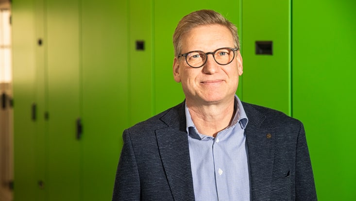 A blonde man stands in front of a plain background in the data center’s server room.